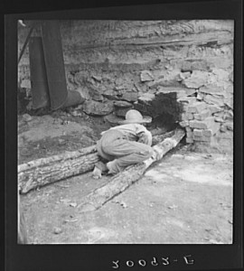 Ten year old son of tobacco tenant tends the fire which is curing the tobacco in the barn. Granville County, North Carolina