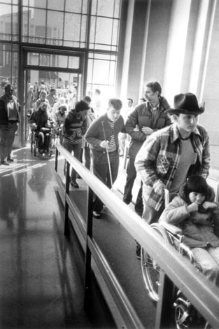 Demonstrators enter San Francisco's regional headquarters of the Department of Health, Education and Welfare for a 1977 sit-in to protest the government's failure to publish regulations for accommodations or to punish institutions that refused to comply with the Section 504 Rehabilitation Act of 1973.  